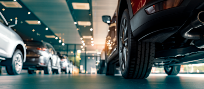 Ein Ausstellungsraum mit mehreren ausgestellten Autos, wobei der Schwerpunkt auf dem Heck eines roten Autos liegt.