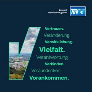 Ein Werbeplakat für "TUEV Hessen" mit dem Slogan "Vielfalt. Verantwortung. Verbunden. Vorauskommen.", begleitet von einer Stadt- und Hügellandschaft.