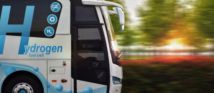 Ein Bus auf der Straße mit dem Schriftzug "Hydrogen" und der Aufschrift "Fuel Cell". Der Bus bewegt sich, und im Hintergrund sind Bäume zu sehen.