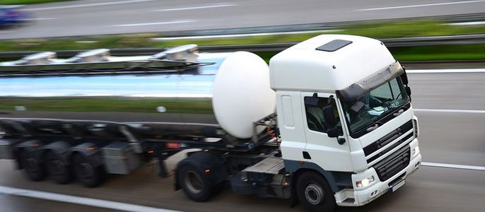 Ein weißer Lastwagen mit silbernem Tankauflieger, der mit hoher Geschwindigkeit auf einer Autobahn fährt.