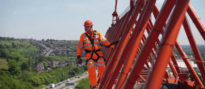 Ein Bauarbeiter der auf einem Krahn steht