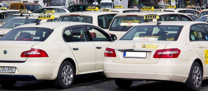 Ein Parkplatz voller weißer Taxis, jedes mit einem gelben Taxischild auf dem Dach.